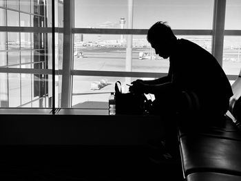 Side view of silhouette man sitting at airport lounge