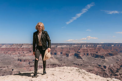 Woman standing on rock against sky