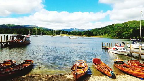 Boats in sea against cloudy sky