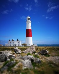 Lighthouse by sea against blue sky