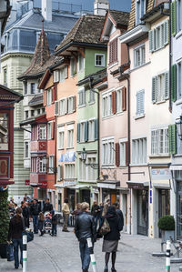 People walking on street amidst buildings in city