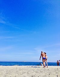 Women on beach against blue sky