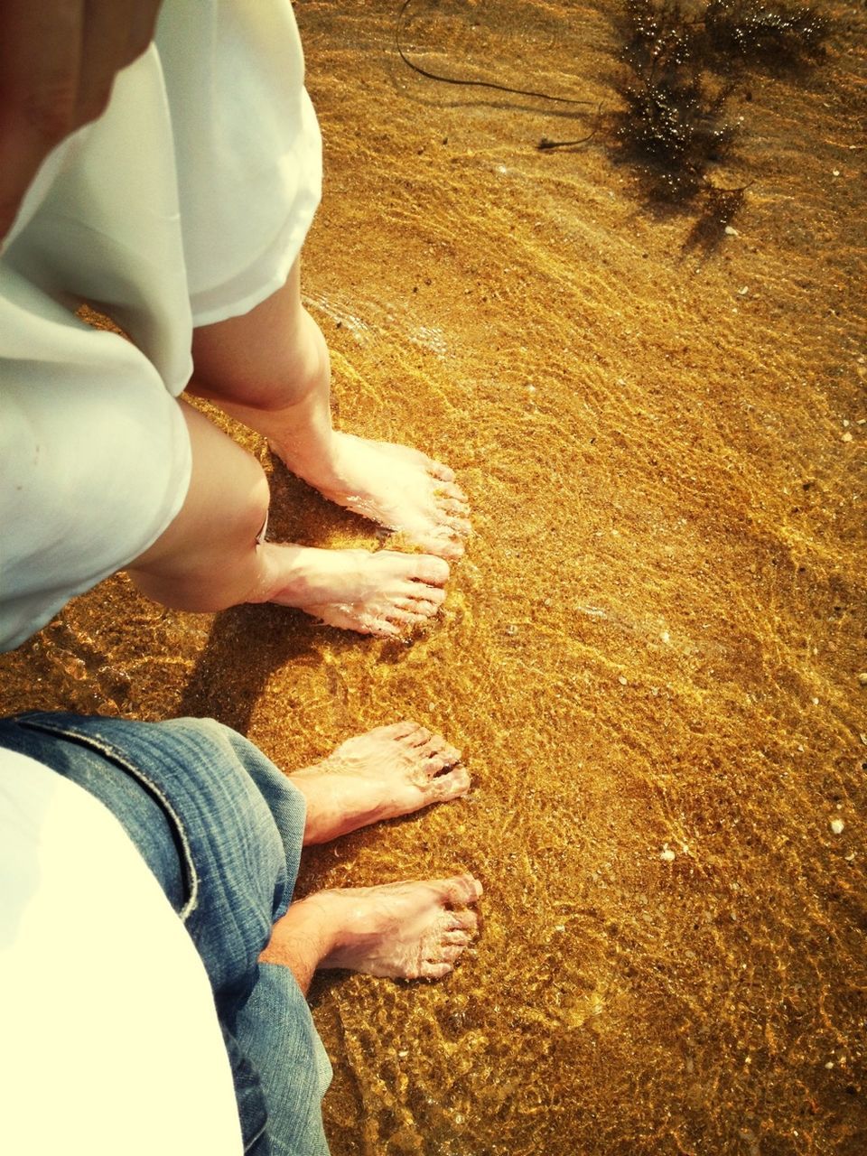 low section, person, lifestyles, sand, leisure activity, beach, human foot, barefoot, personal perspective, standing, high angle view, water, sunlight, shoe, shore, part of