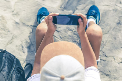 Top view of young boy watching video on smartphone. hipster male enjoying podcast outdoors alone