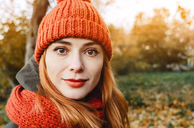 Autumn portrait of stylish woman in orange warm knitted hat and orange scarf. romantic look