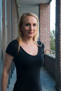 Portrait of smiling young woman standing against wall