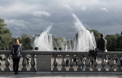 People standing on fountain against waterfall