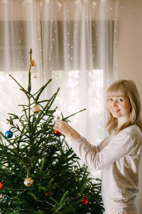 Portrait of young woman standing by christmas tree