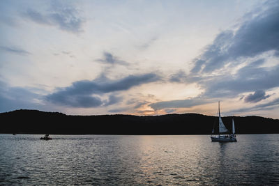 Sailboat sailing on sea against sky during sunset