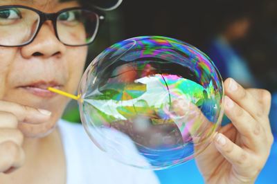 Close-up portrait of woman blowing transparent balloon