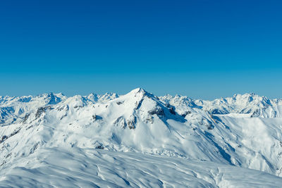 Scenic view of snowcapped mountains against clear blue sky