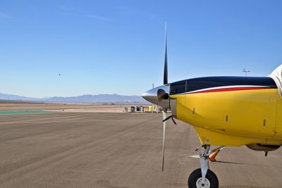 Airplane on airport runway against clear blue sky