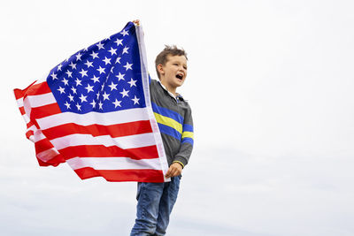 Portrait of woman holding american flag against clear sky