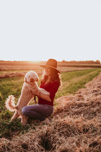 Happy woman playing with dog on farm