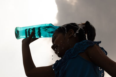 Rear view of woman holding bottle against white background