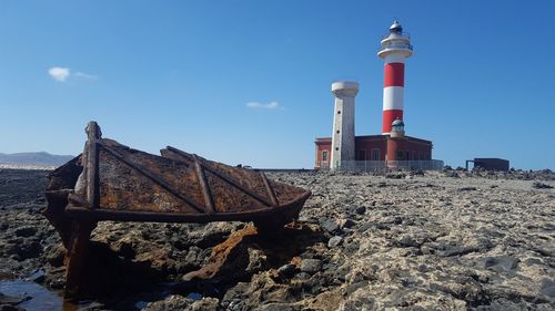 Lighthouse on beach against sky