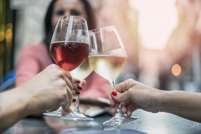 Midsection of adults clinking wineglasses