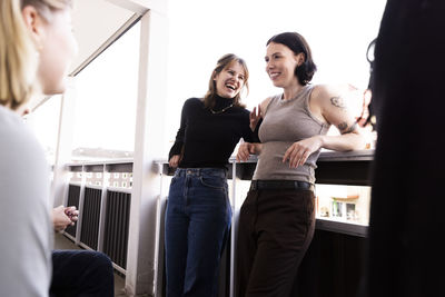 Happy young female friends laughing and having fun in balcony