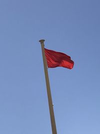 Low angle view of flag against clear blue sky