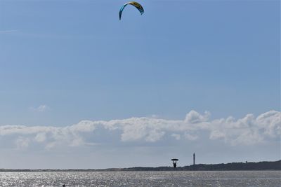 Person paragliding over sea against sky