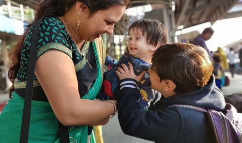 Midsection of woman holding baby at railroad station platform