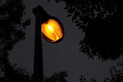 Low angle view of illuminated street light against sky