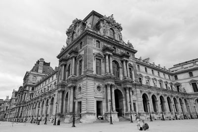 Low angle view of musee du louvre against cloudy sky