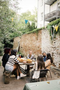 Male and female friends communicating with each other at dinner party in back yard