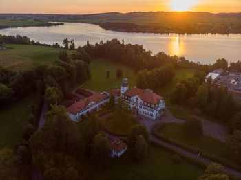 High angle view of lake by buildings against sky during sunset