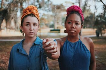 Portrait of young women holding hands while standing at park