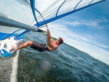 Wide-angle shot of adult man windsurfing on lake wallersee, austria.