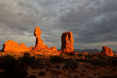 Rock formations on landscape against cloudy sky