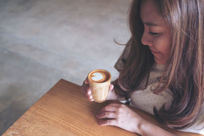 High angle view of woman holding coffee cup on table