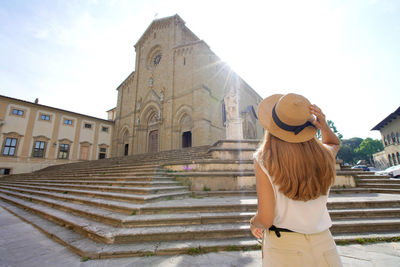 Rear view of young tourist woman in piazza duomo square in the old town of arezzo, tuscany, italy.