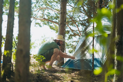 Caucasian man wearing a hat putting up a tent. family camping concept