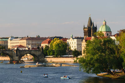 Buildings by river against sky in city