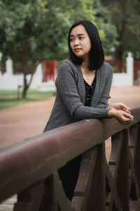 Portrait of young woman sitting on railing