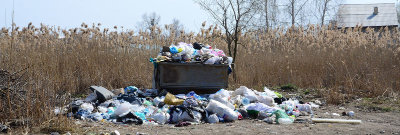 Group of people on garbage at field against sky