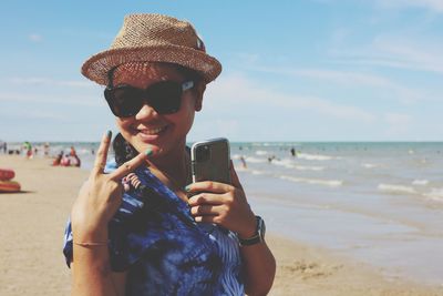 Portrait of mature woman holding mobile phone at beach