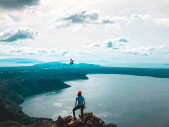 Rear view of a woman standing on a mountain against the sky, a beautiful view, and a butterfly. 