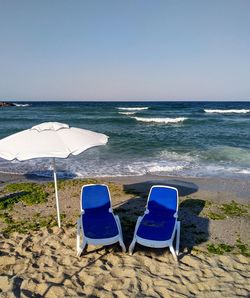 Deck chairs on beach against clear sky