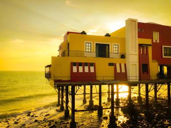 Lifeguard hut on beach by sea against sky during sunset