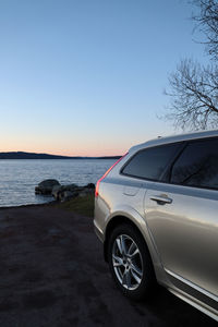 Car on road by sea against clear sky