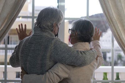 Rear view of couple standing against wall