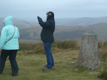 Rear view of couple on landscape against sky