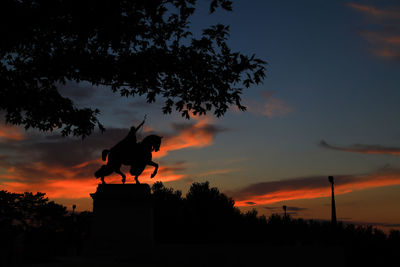 Silhouette statue against sky during sunset