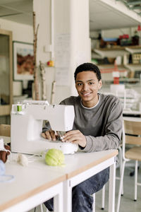 Portrait of smiling teenage male student during sewing class at high school