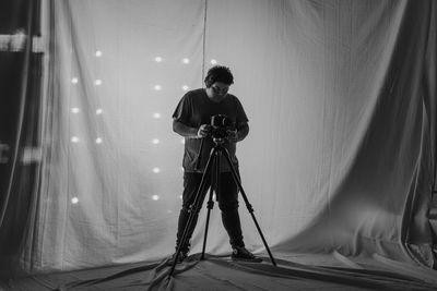 Man photographing while standing against curtain