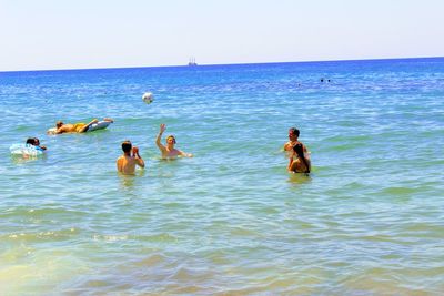 People swimming in sea against clear sky