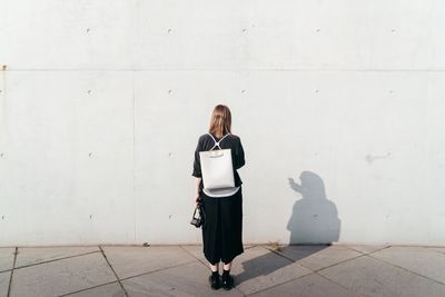 Full length of woman standing against wall